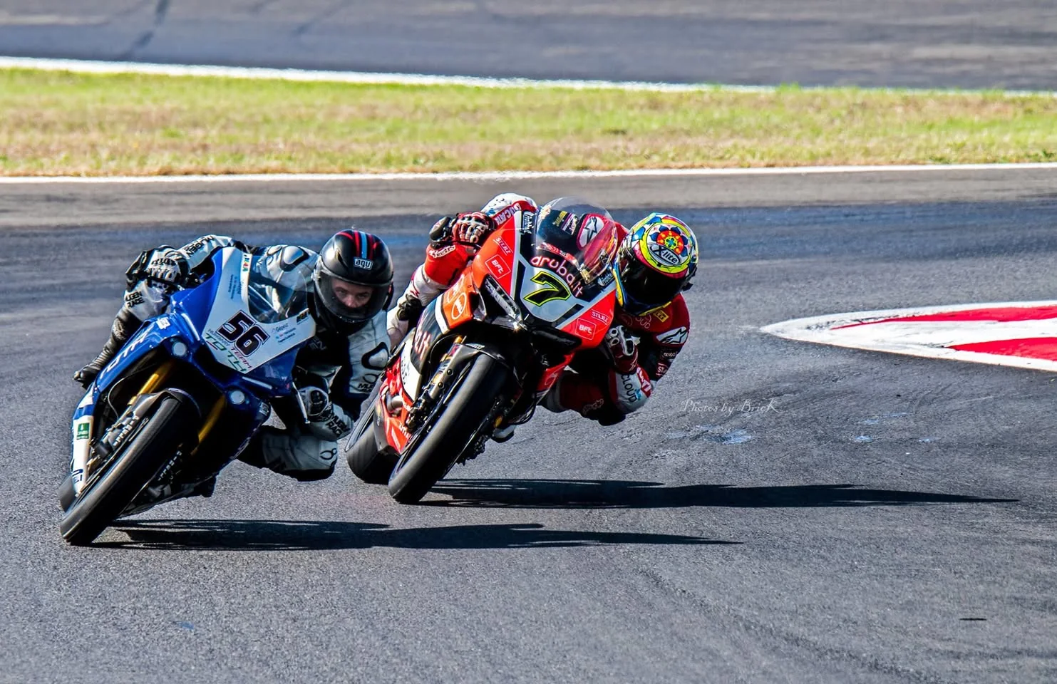 Two motorcycle racers lean through a corner, close together on the track.