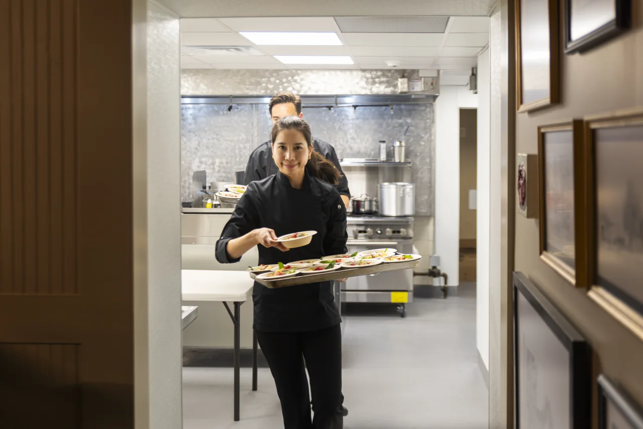 A restaurant server carries plates through a doorway.