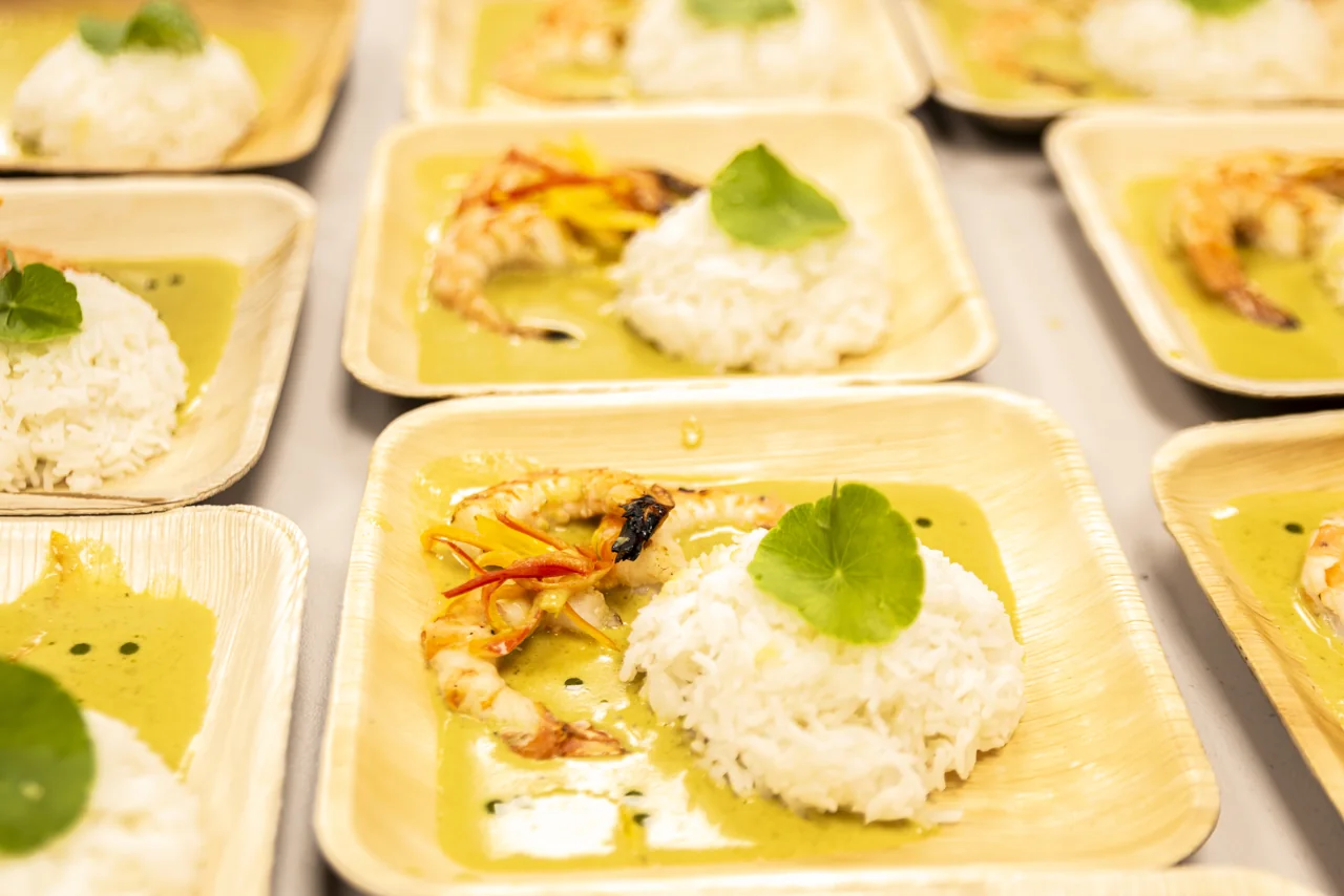 Plates of curry, rice and herbs are arranged for service.