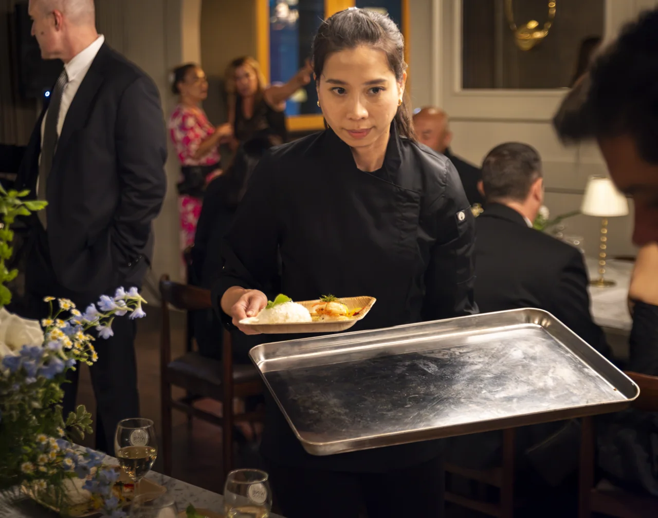A focused server carries a prepared dish through the dining room.