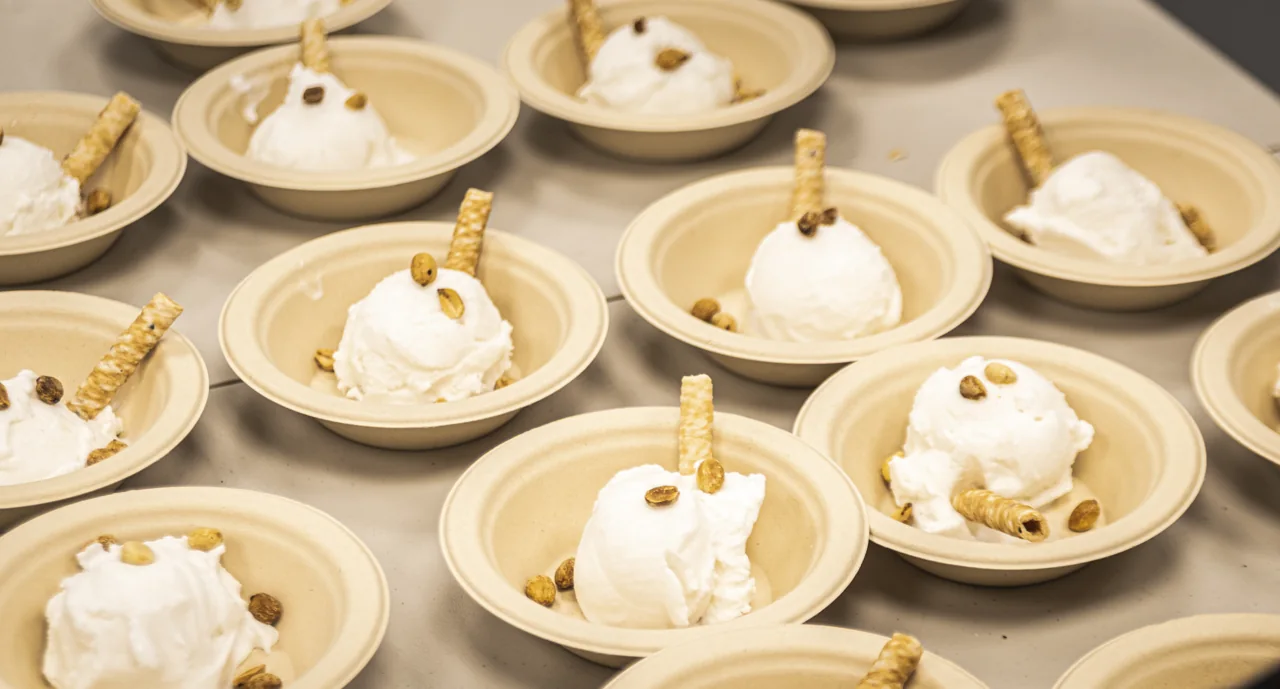 A row of desserts is topped with scoops and small wooden spoons.