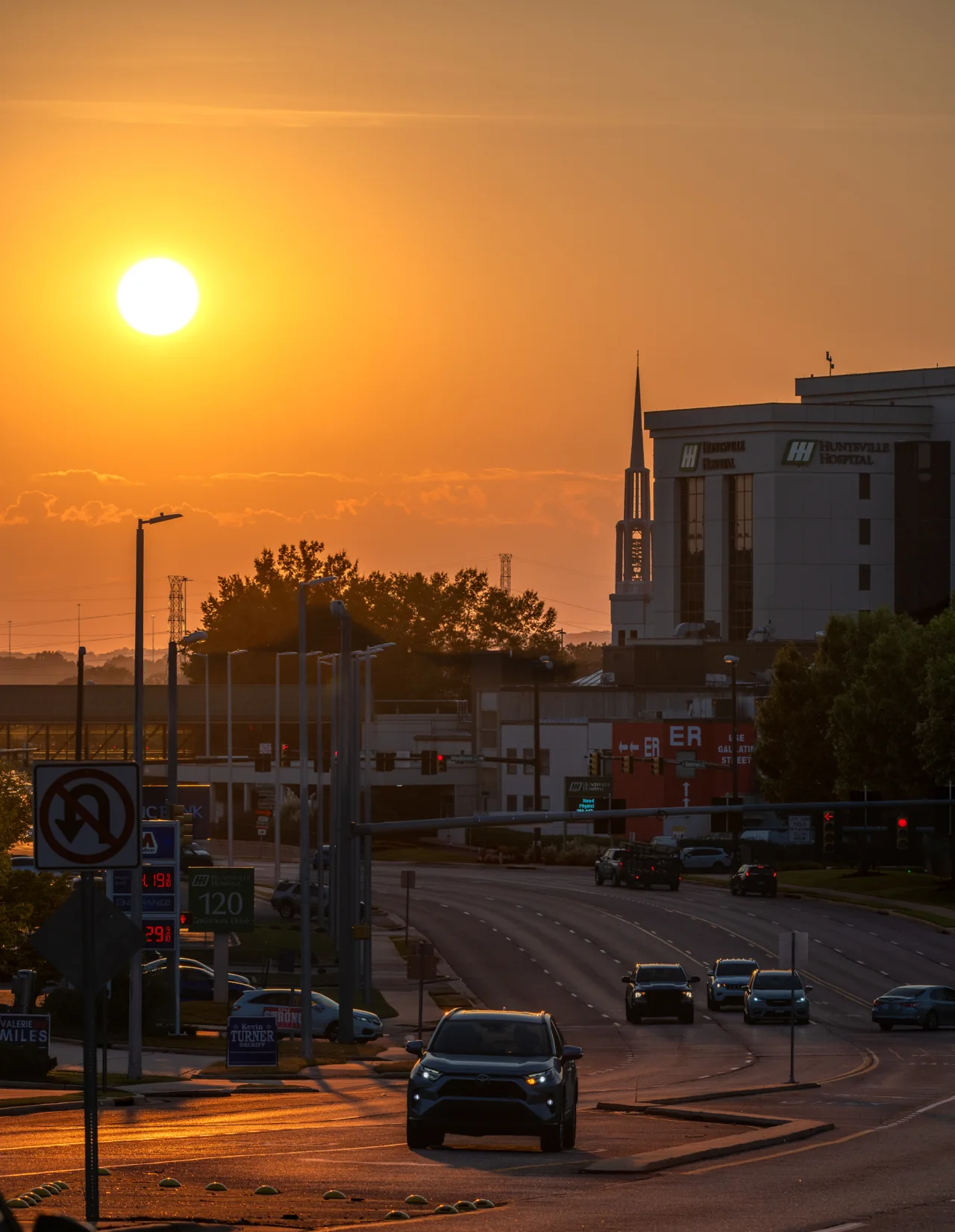 The orange sun hangs above silhouetted rooftops and an urban street.