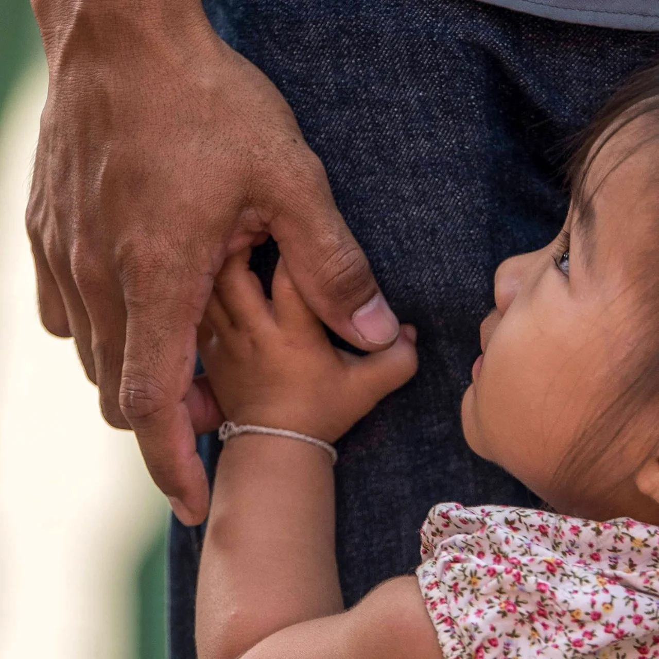 A child holds an adult's hand in a close-up outdoor photograph.
