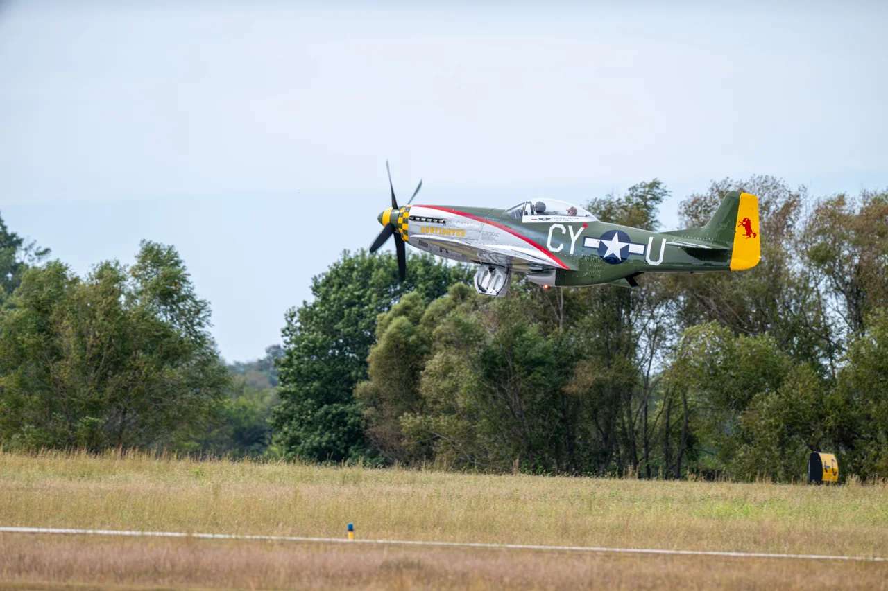 A vintage aircraft lifts above a runway.
